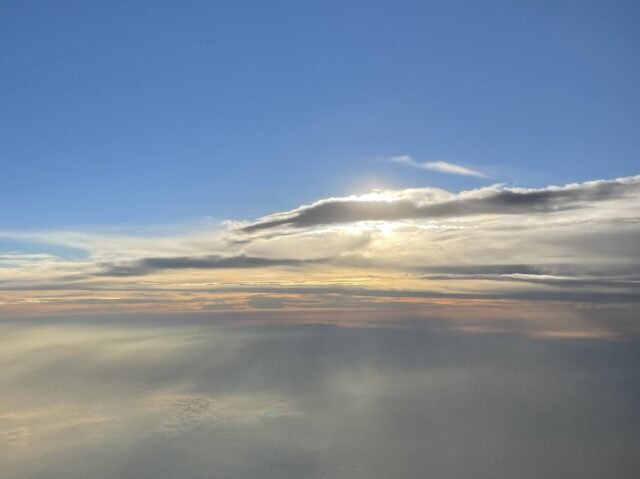 Blue sky with cloud obscured sun from plane window