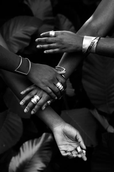 Photo of Black women's hands reaching for each other wearing silver jewelry