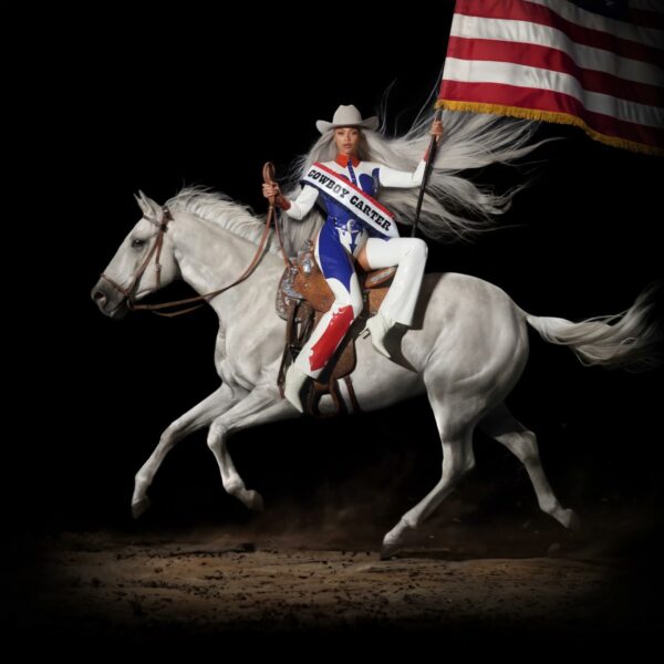 Cowboy Carter album cover, Beyonce dressed as a rodeo queen on a white horse holding a partially visible American flag.