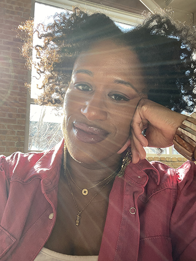 Author in open pink button up with a white tank and gold necklace. Sunburst in the upper left corner of the photo.