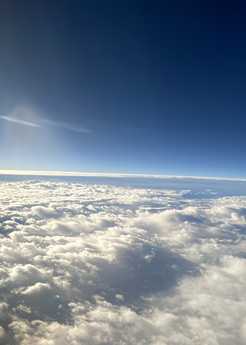 Clouds and a blue sky from an airplane window.