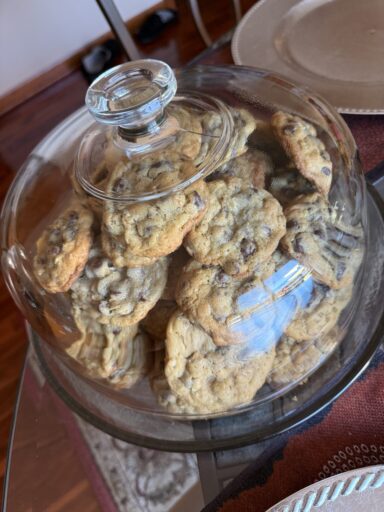 Chocolate chip oatmeal cookies under a glass serving dome. Baked by the author.