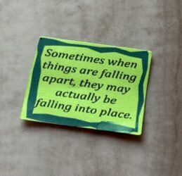 Green piece of paper that says "Sometimes when things are falling apart, they may actually be falling into place."